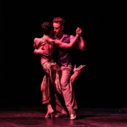 dunkler Hintergrund, ein rosa beleuchtetes Paar tanzt Tango